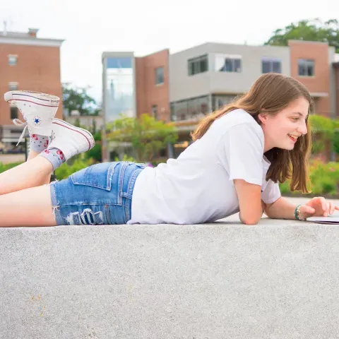 A UNE student works on her laptop outside the Danielle N. Ripich Commons